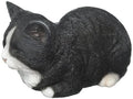 Sleeping cat statue close-up: black fur with white muzzle and paw details
