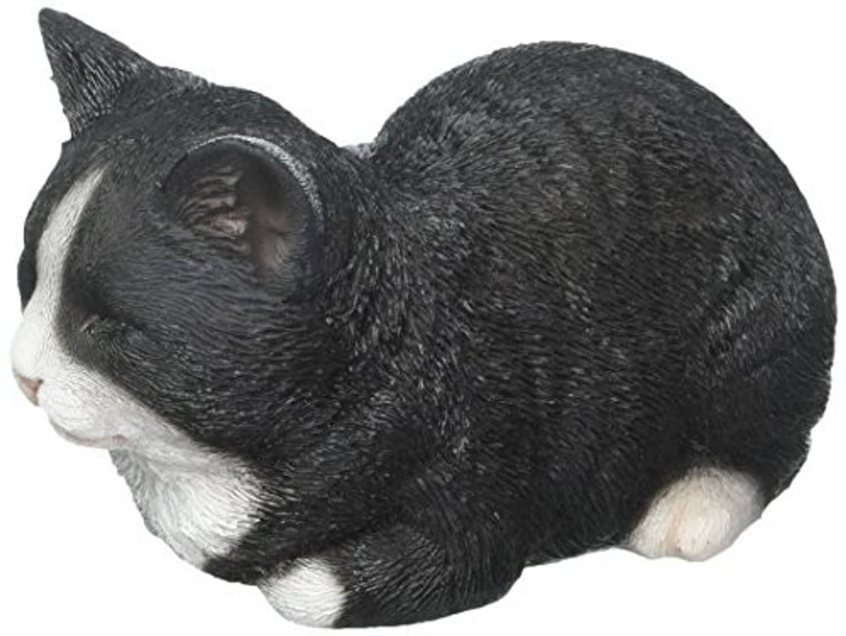 Sleeping cat statue close-up: black fur with white muzzle and paw details