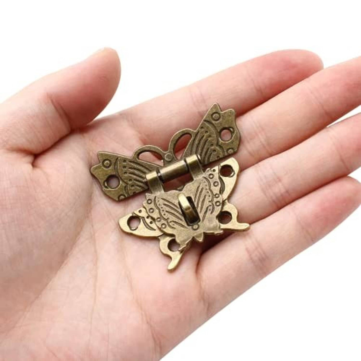 Antique brass butterfly hasp latch held in hand, with a central keyhole