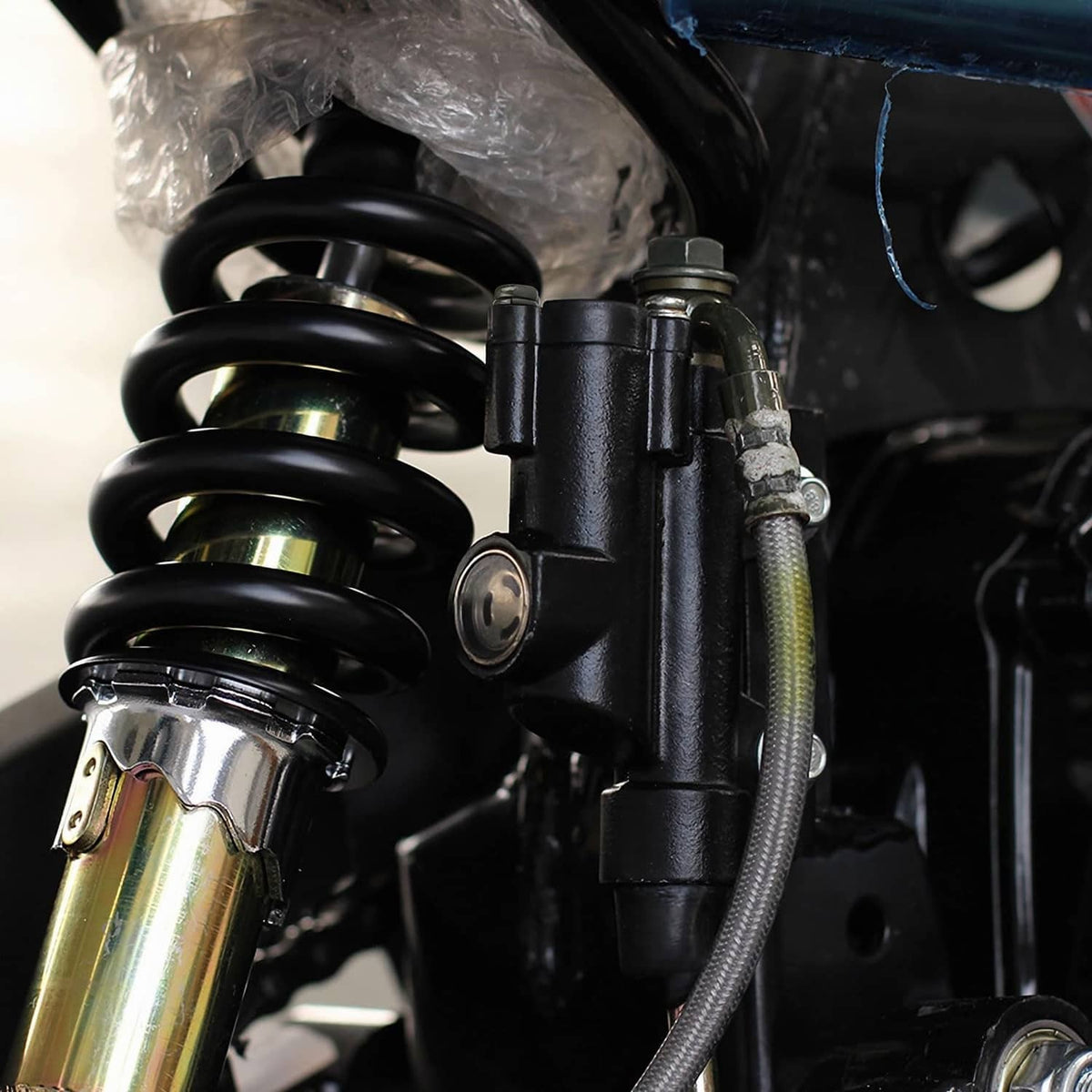 Black rear brake master cylinder assembly with gold hose connector and mounting hardware