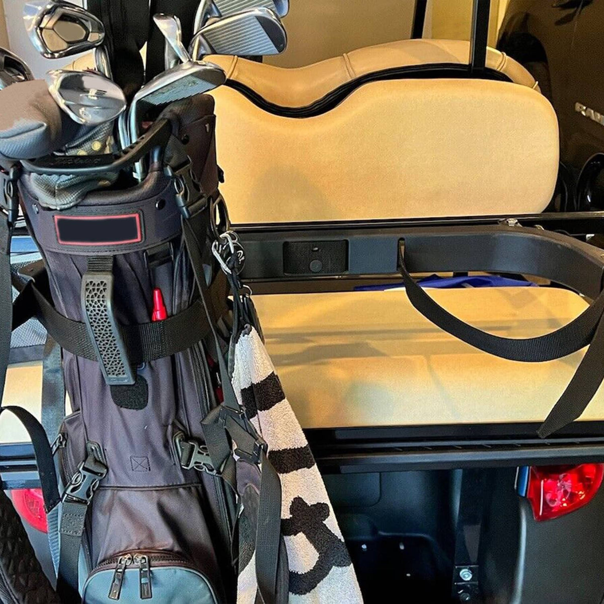 Black bag holder bracket and straps securing a golf bag beside the rear seat