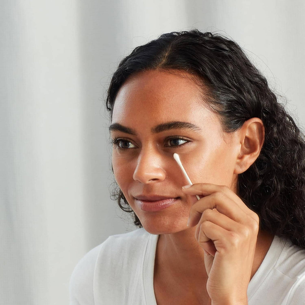 Double-tipped cotton swab held to skin for personal care
