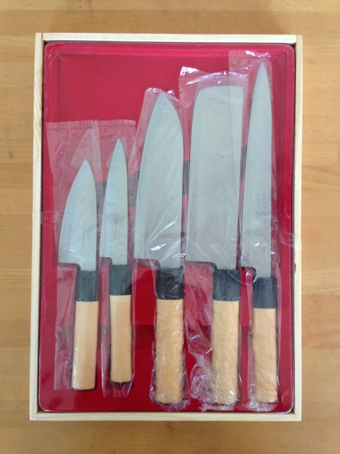 Japanese kitchen knife set boxed and wrapped, showing five light wood-handled knives