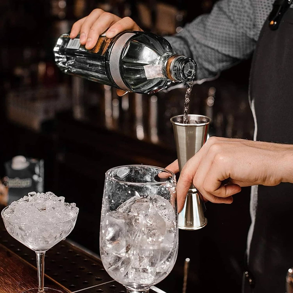 Stainless steel jigger held above ice during bartending preparation