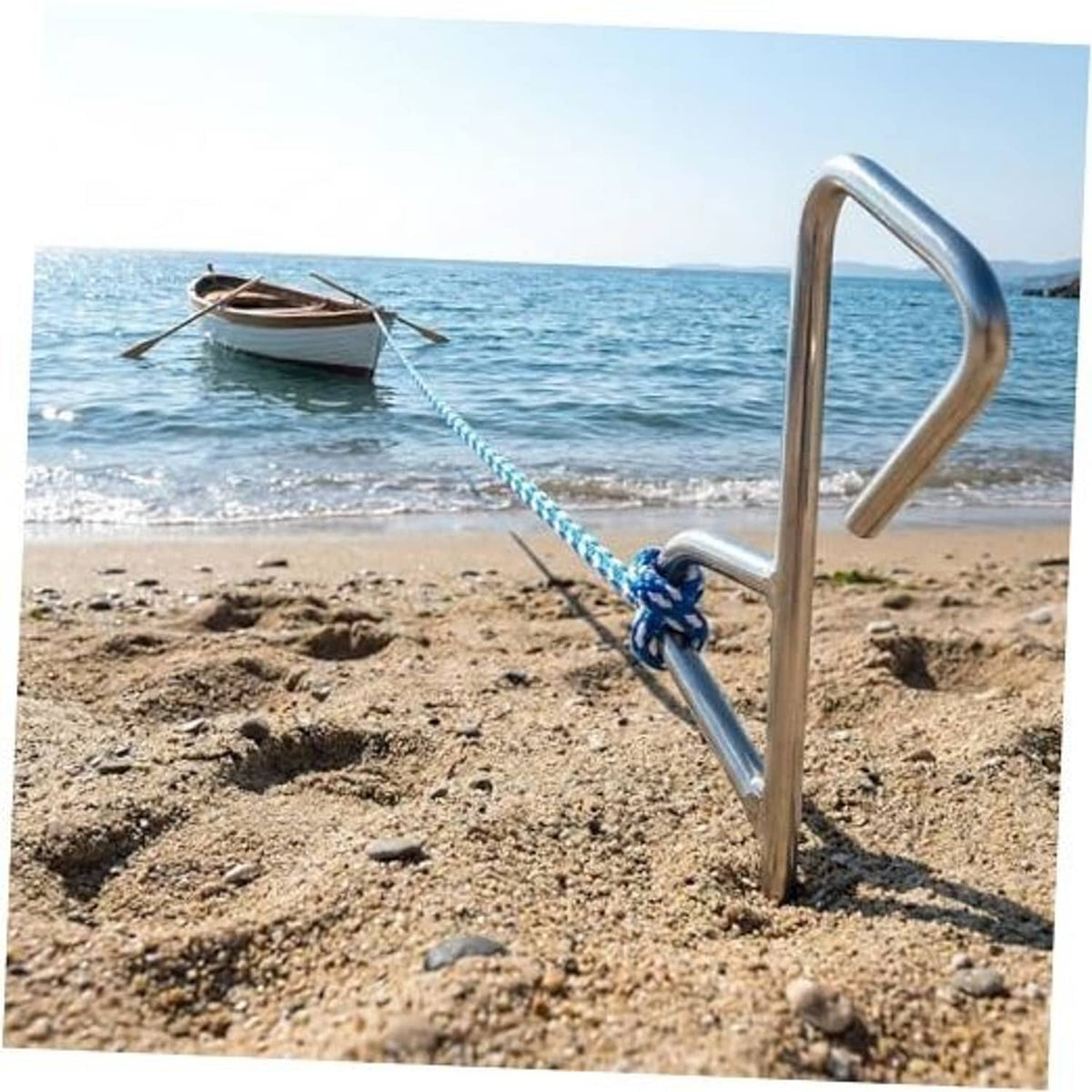 Chrome boat sand spike anchor with chain and rope knot in beach sand