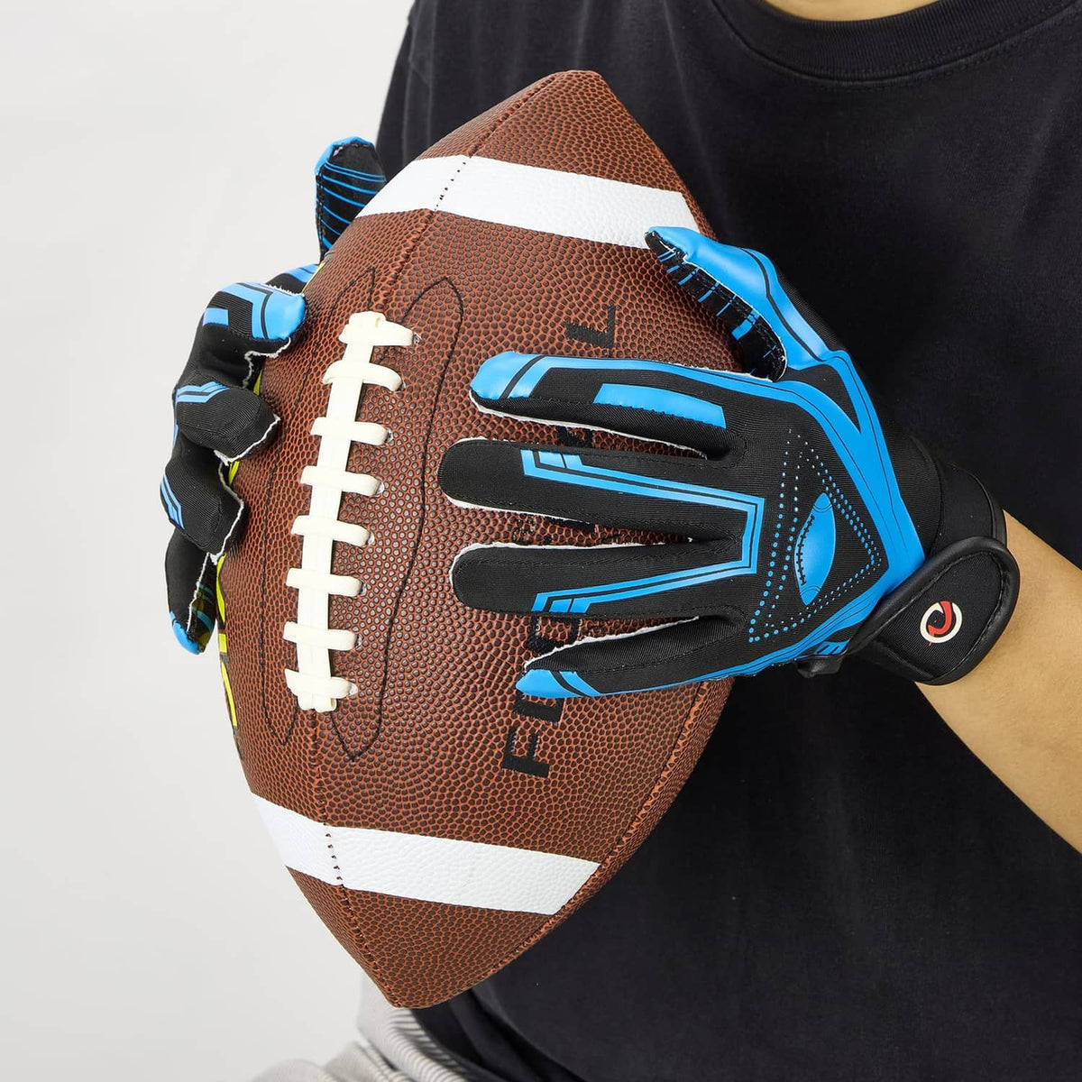 Youth receiver glove gripping a football; black palm with blue silicone grip lines