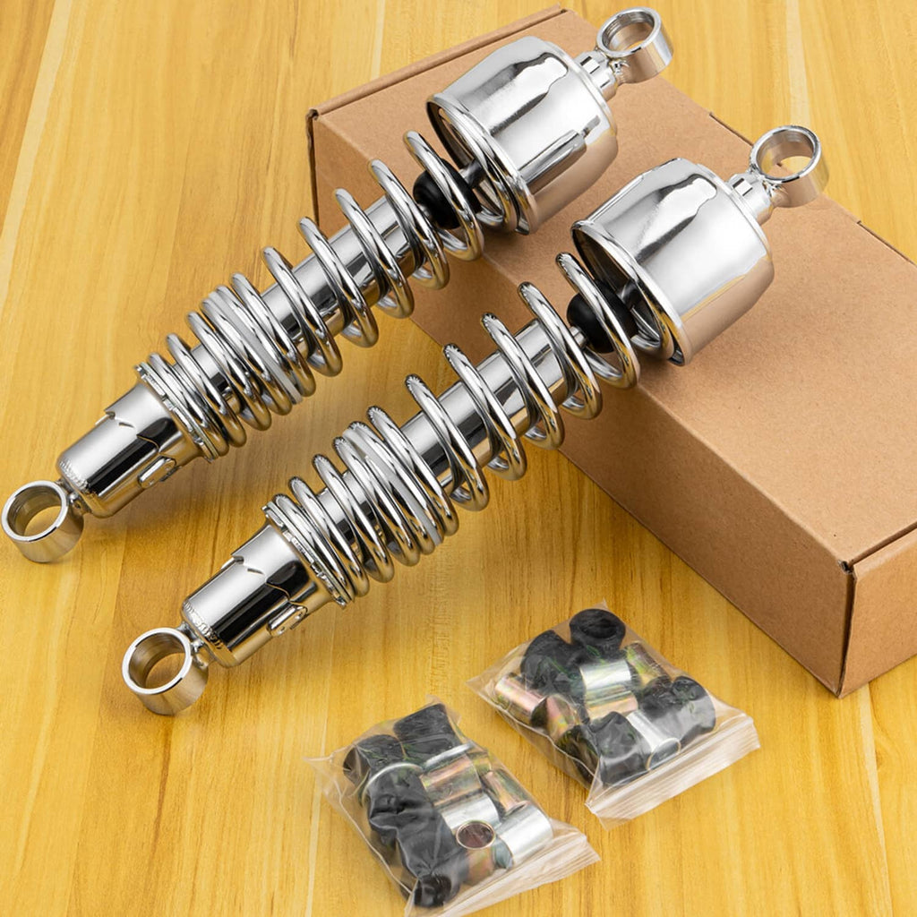 Two chrome 13-inch rear shocks laid out on a box with mounting hardware packs