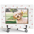 White dog photo frame with multicolor paw prints and bones, on black metal stand.