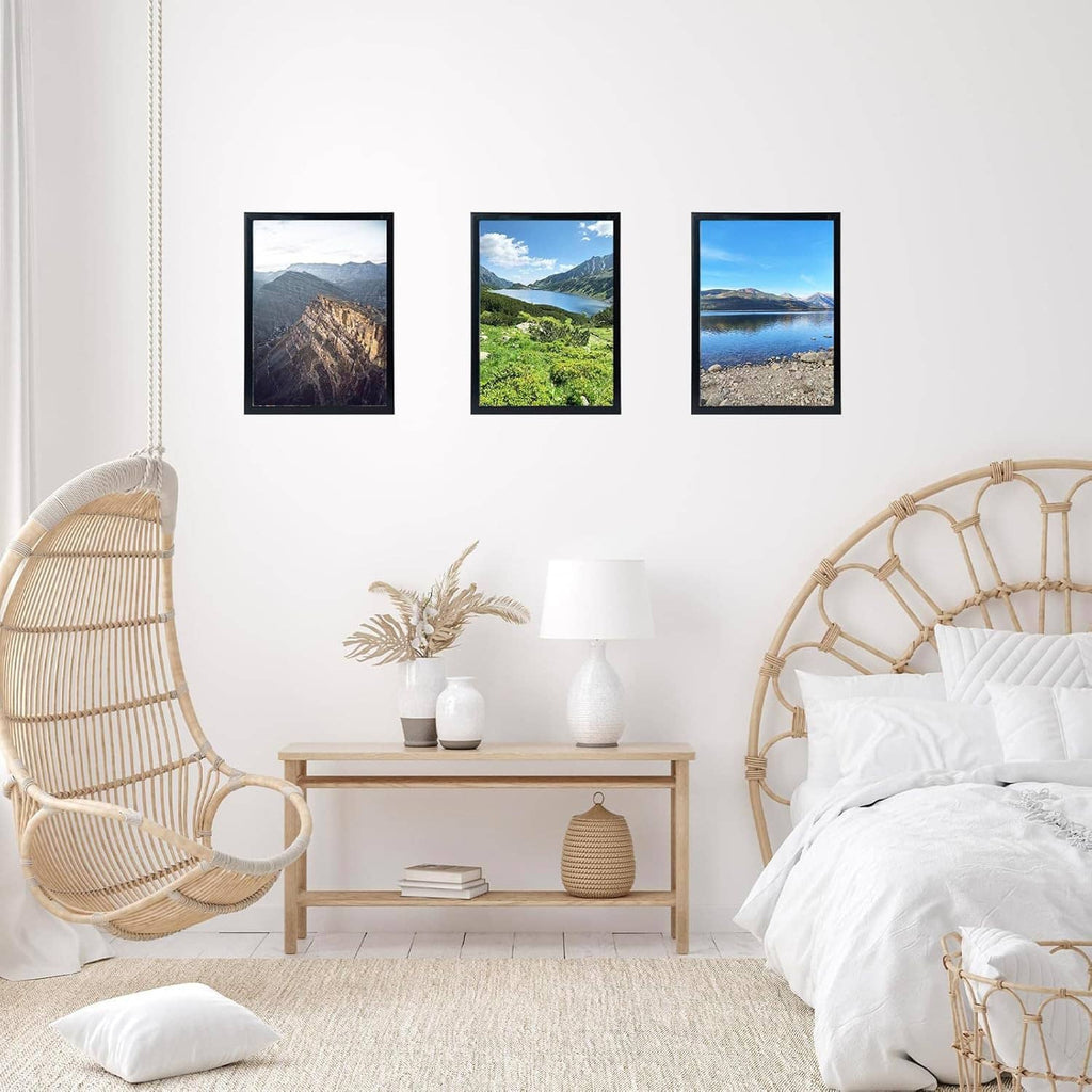 Black picture frames on white wall showing three landscape photos