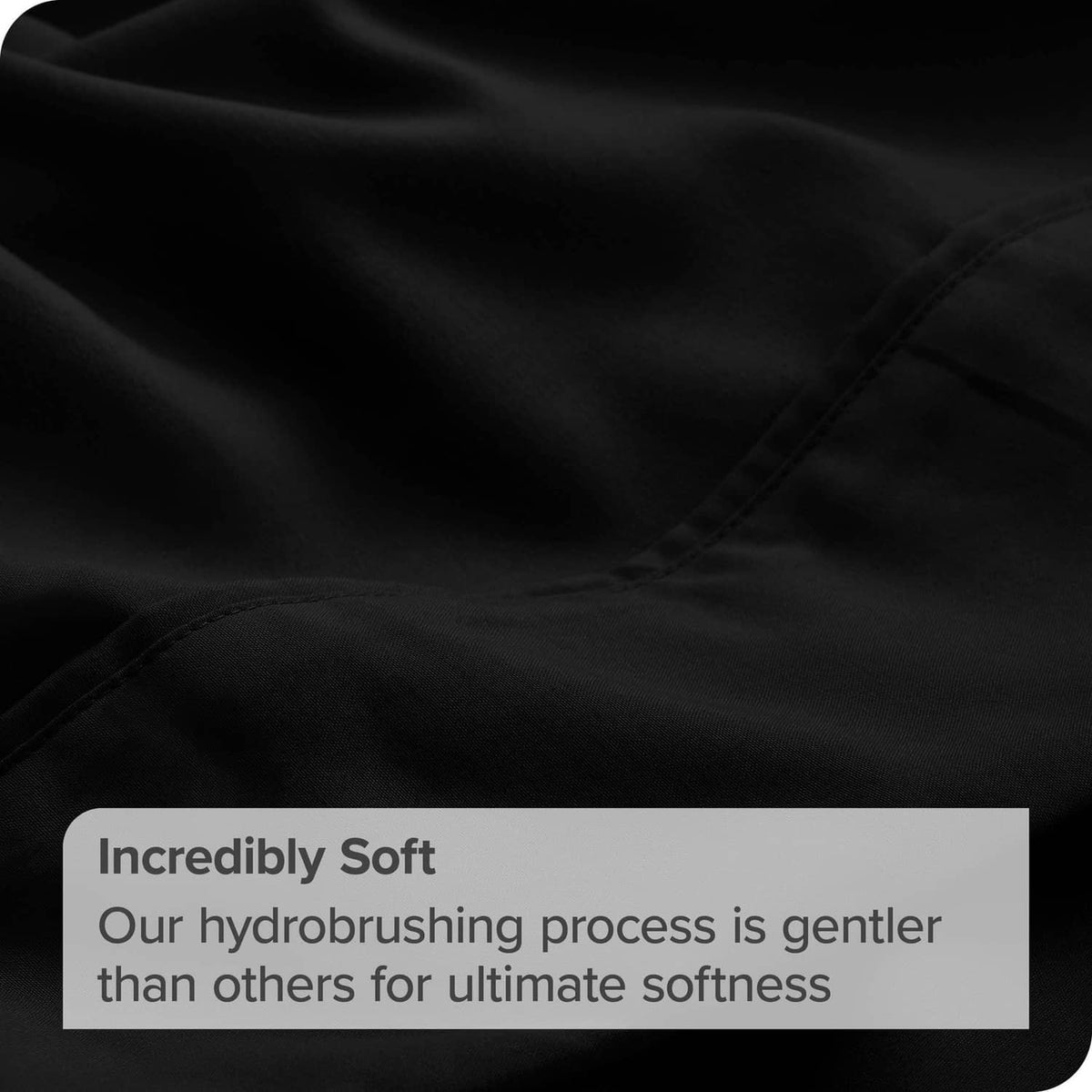 Close-up of black microfiber flat sheet fabric with visible seam and stitching.