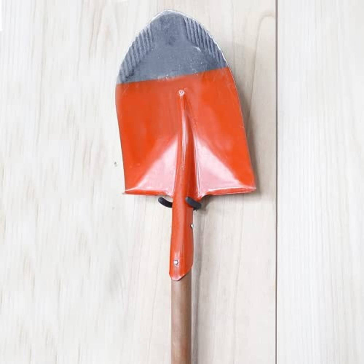 Screw-in U hook mounted on a wood surface, holding a red-handled garden tool.