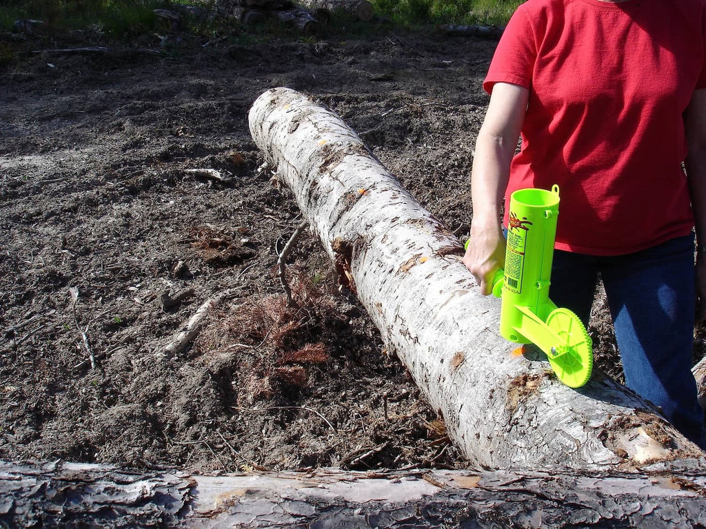 Green firewood measuring marker placing white marks on a log outdoors.