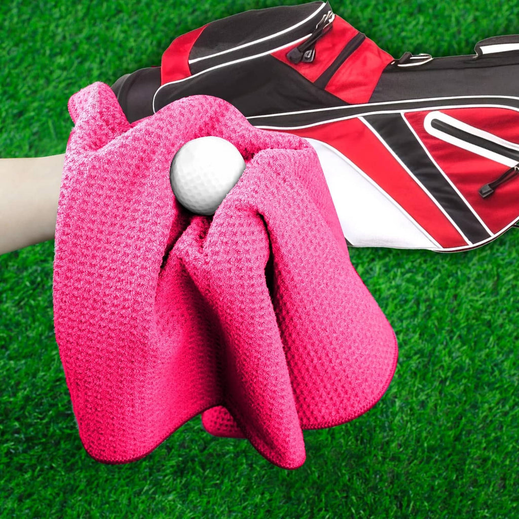 Pink golf towel with textured surface and metal ball for golf club cleaning