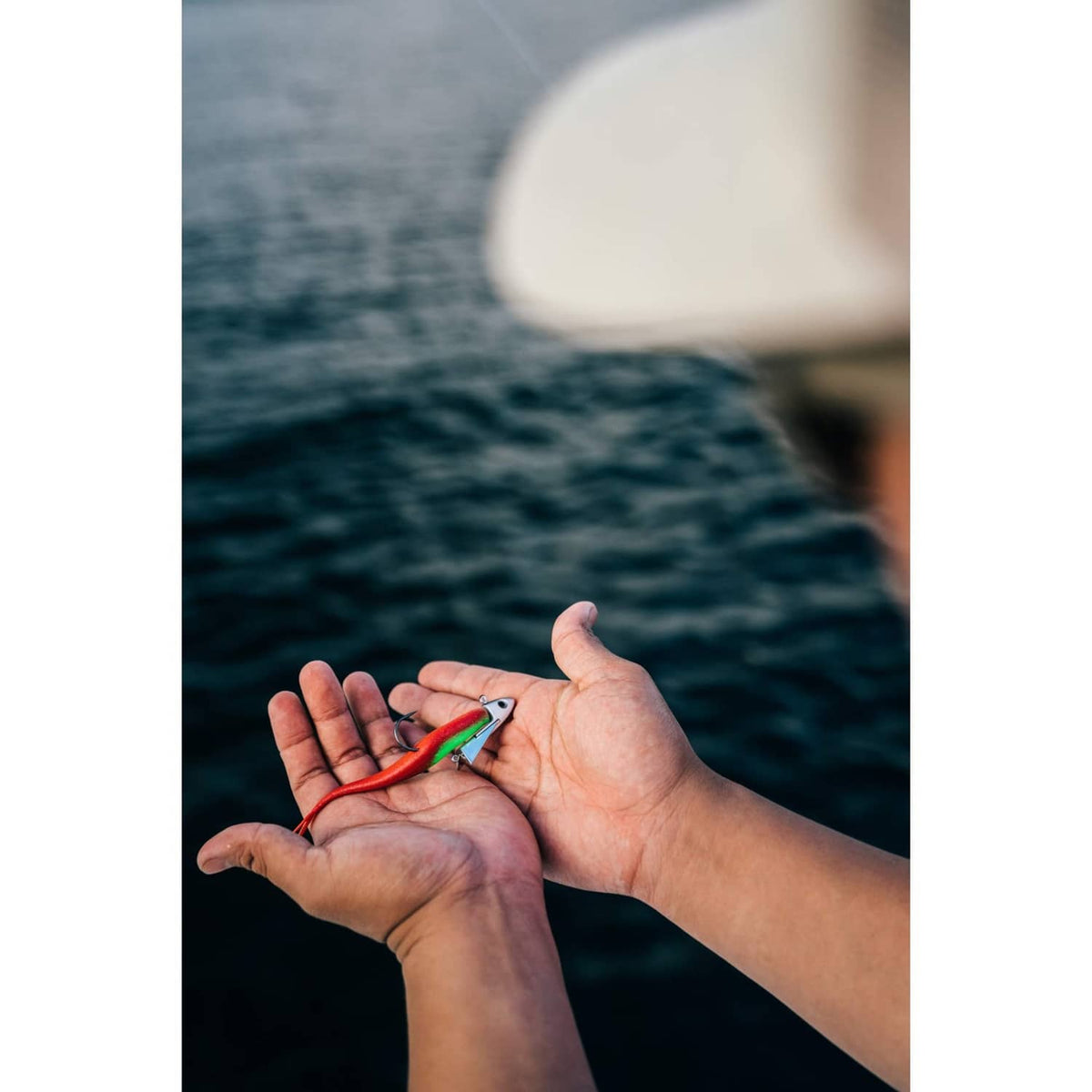 Chartreuse pepper jerk shad lure with red tail resting in open hands