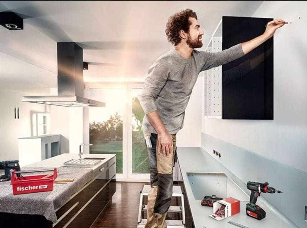 Person installing fischer UX expansion plug on a wall with drill and boxes