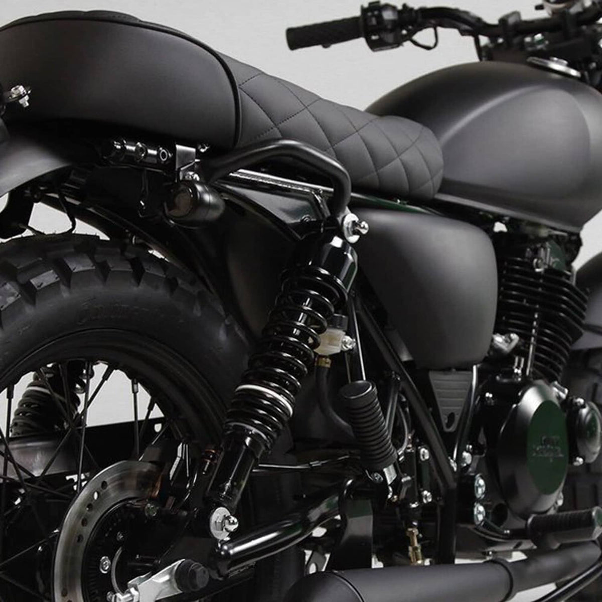 Black rear shocks and coil springs near the motorcycle seat and wheel area