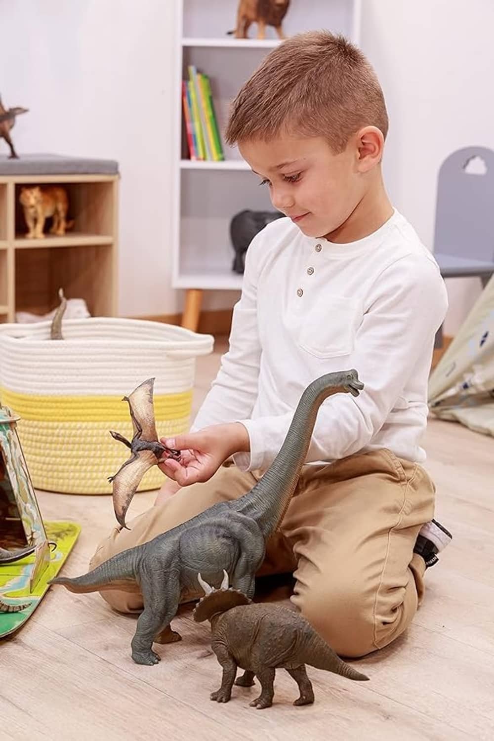Compsognathus dinosaur figurine held by a child during play with other dinosaurs.