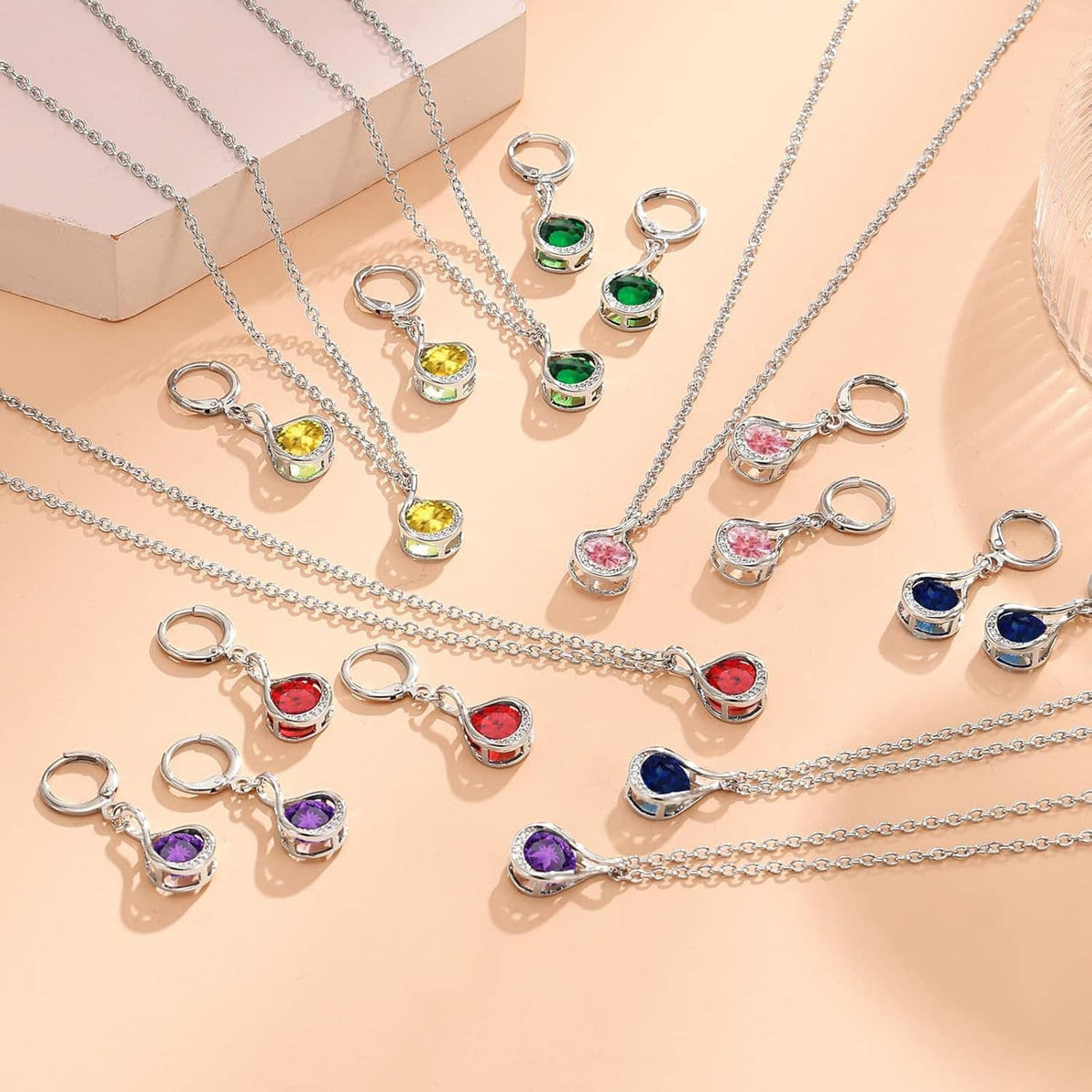 Assorted silver charm necklaces with colorful teardrop gemstones and small hoop clasps
