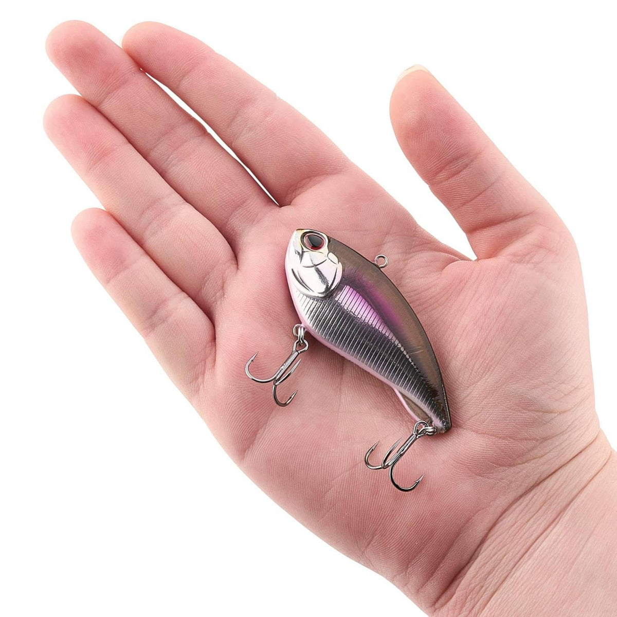 Fishing lure resting in hand: silver and purple body with two treble hooks