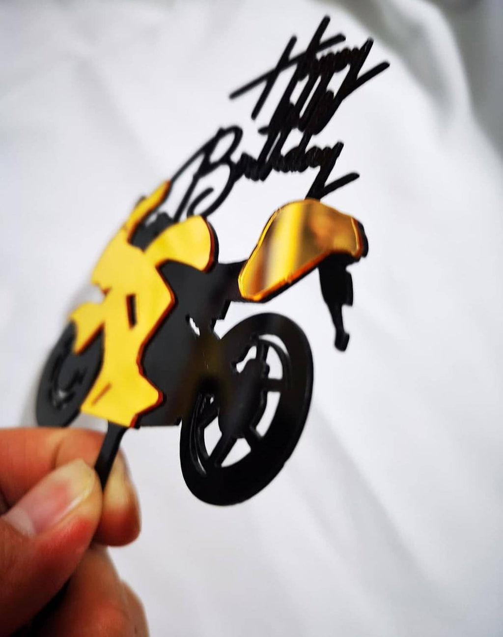 Close-up of motorcycle cake topper showing yellow accents and 'Happy Birthday' lettering