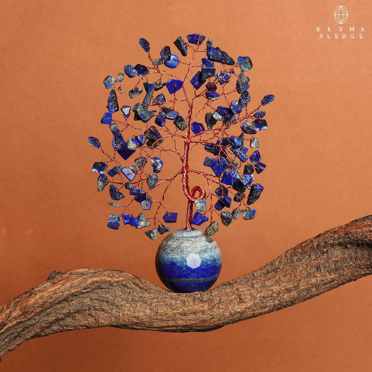 Lapis lazuli Tree of Life ornament with round blue stone base resting on a branch