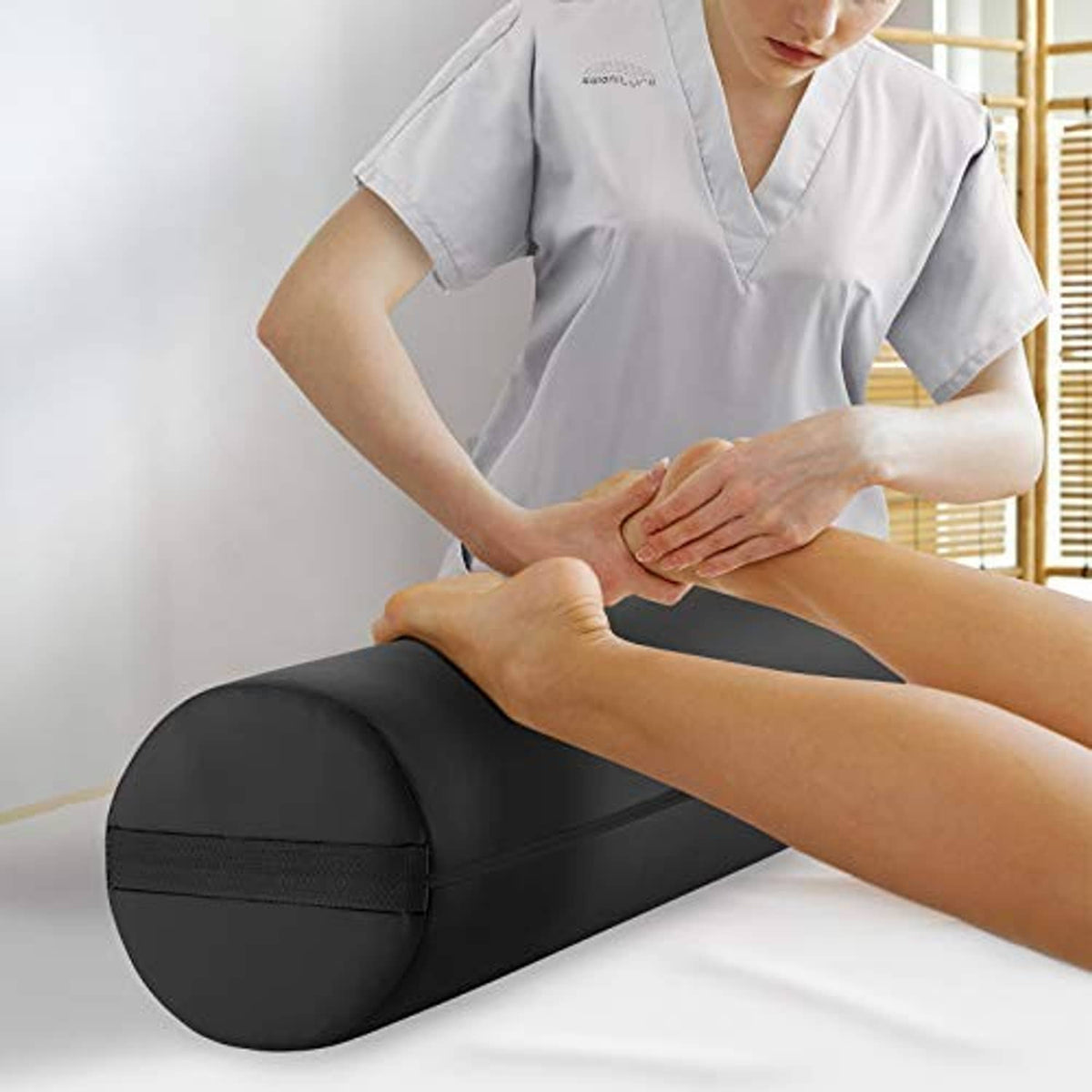 Black massage table bolster pillow pad supporting an arm during bodywork