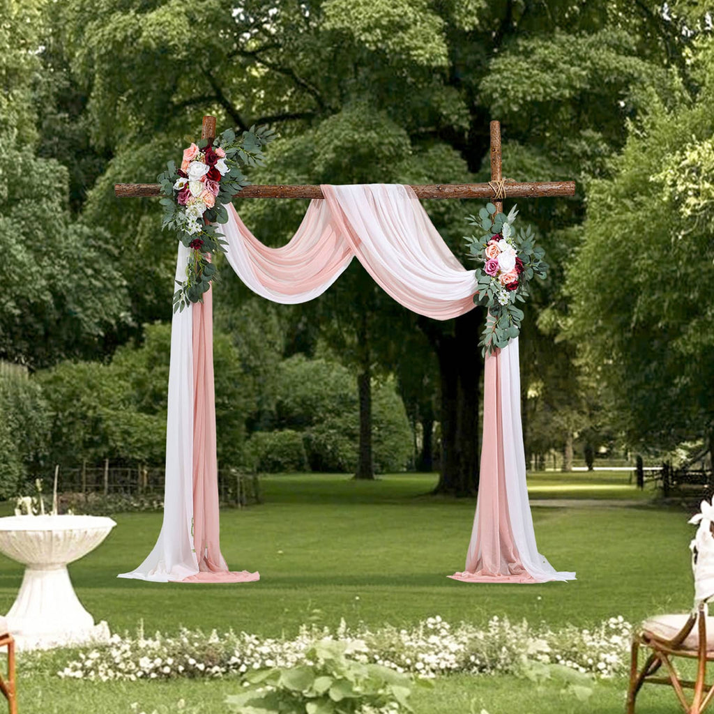 Outdoor wedding arch with faux pink floral arrangements and sheer white-pink drapes