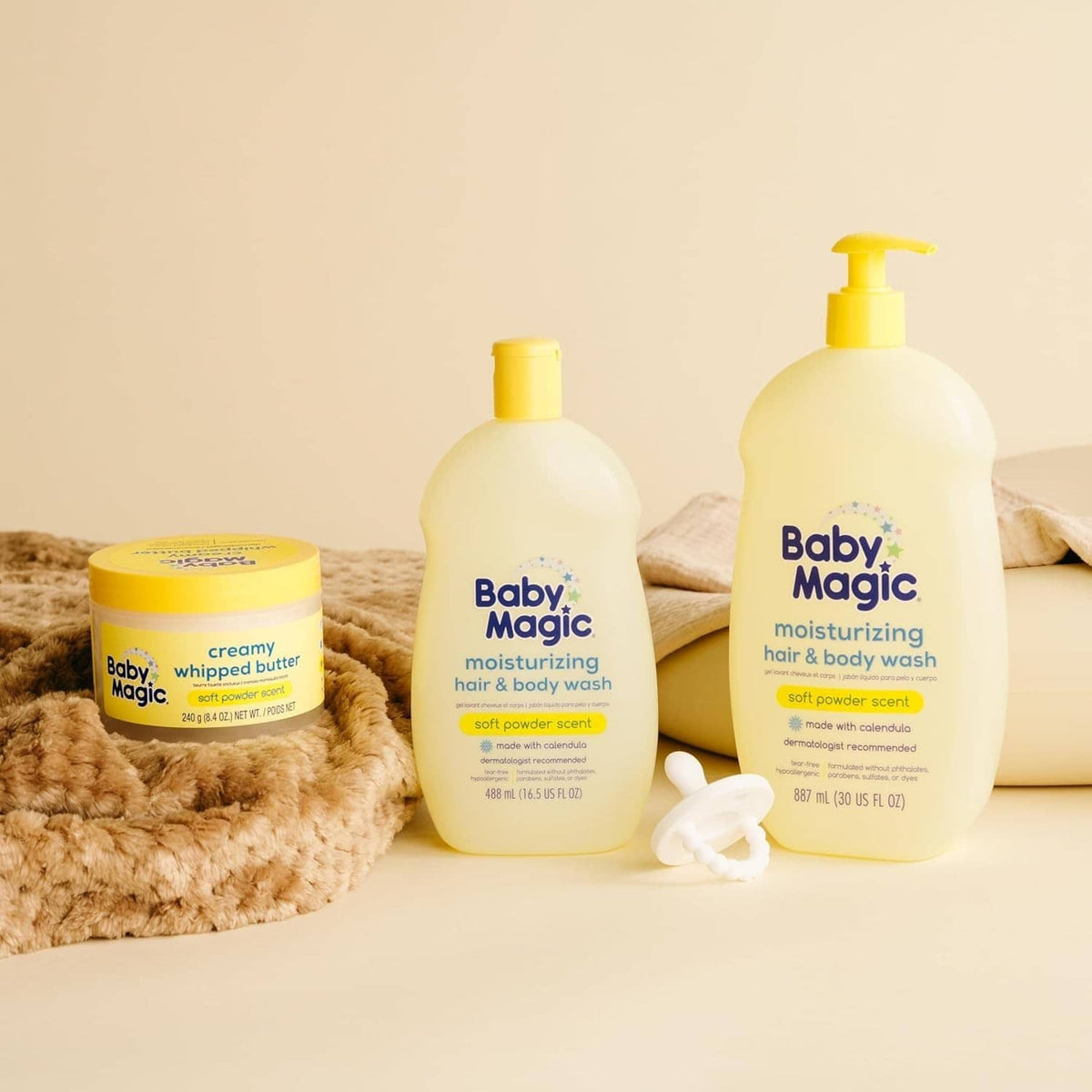 Baby Magic hair & body wash bottles and cream jar on soft towels.