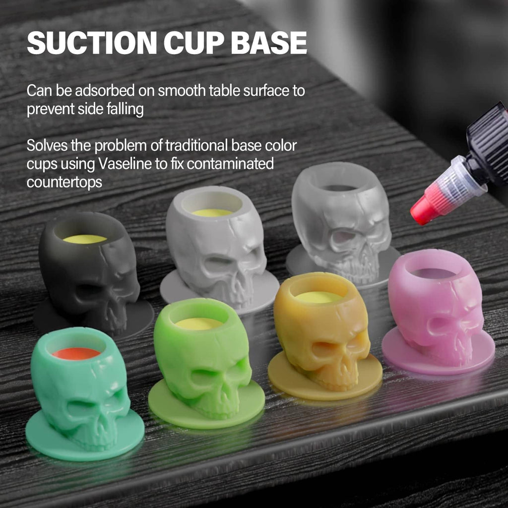 Skull-shaped silicone tattoo ink cups with suction-cup bases in gray, pink, green, and yellow.