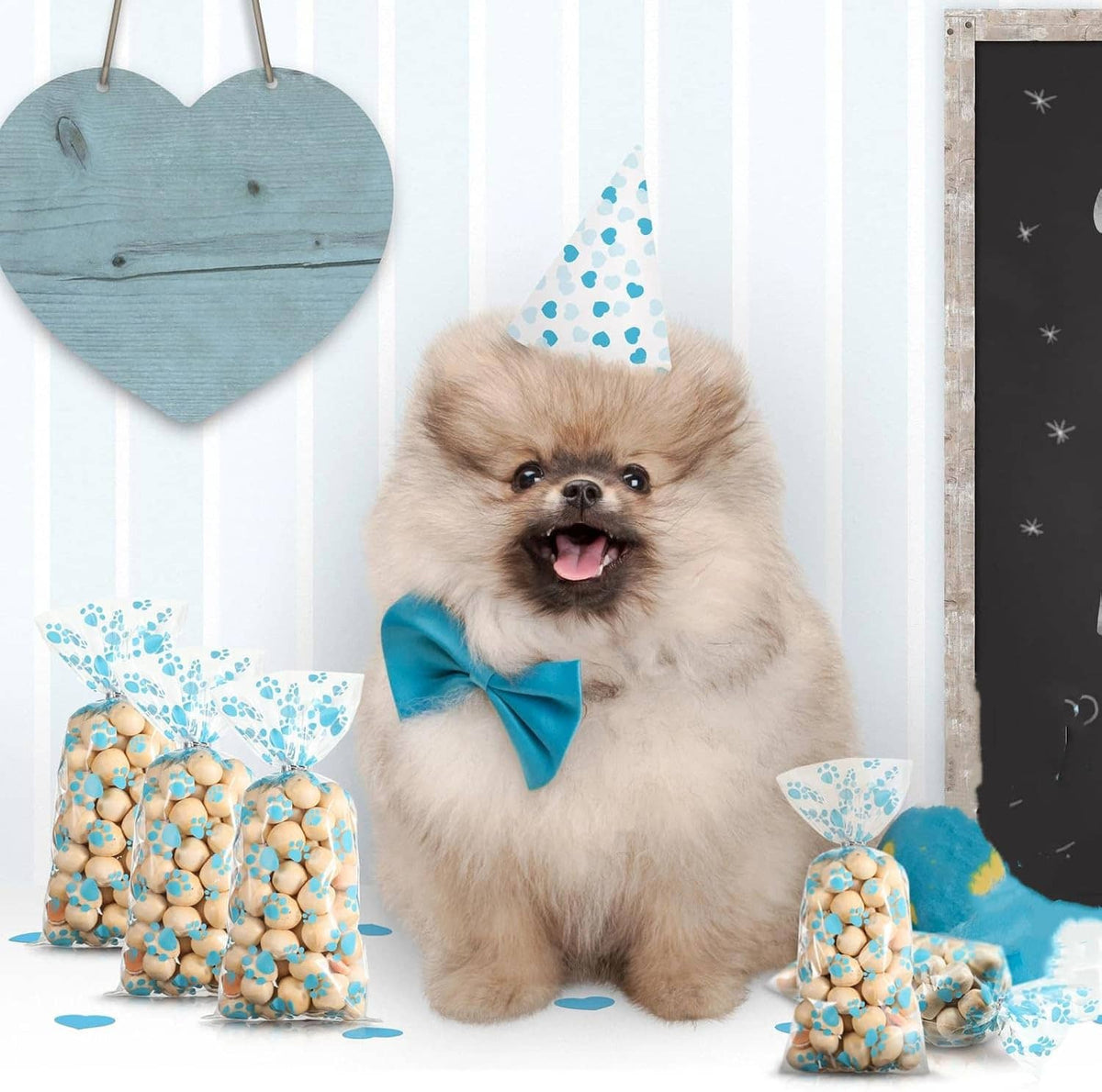 Dog treat cellophane bags with blue paw prints, arranged beside a small dog wearing a blue bow.