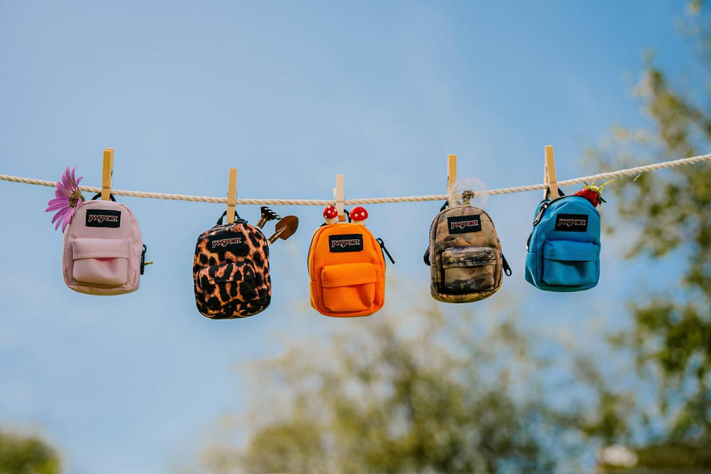 Pink mini backpack with JanSport logo hanging from clothesline