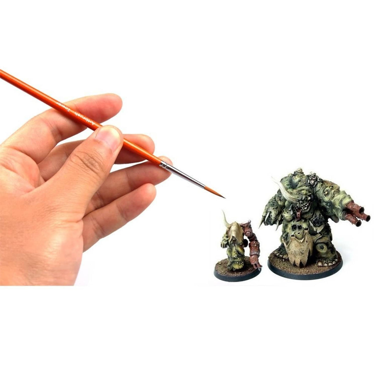 Hand holding a small detail paint brush with orange handle and fine tip