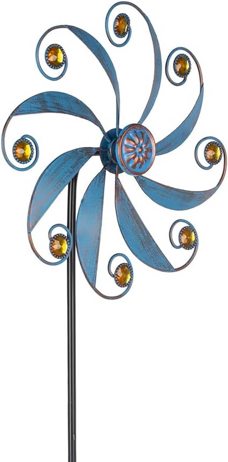 Blue metal wind spinner with curved blades and jeweled center, gold accents, on tall black pole.