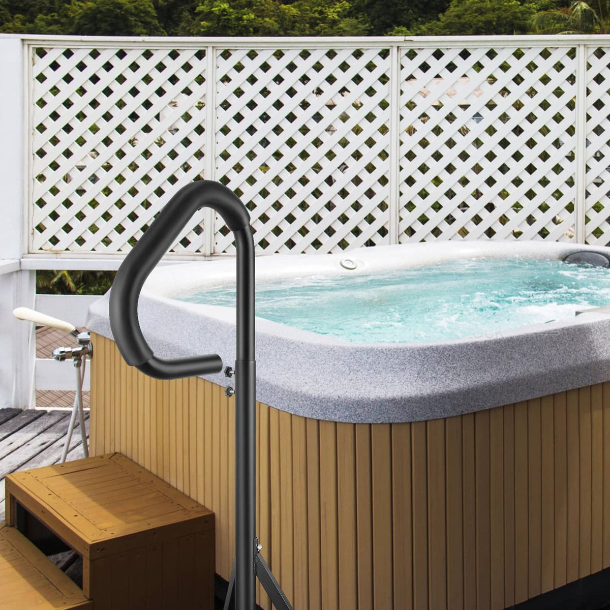 Black hot tub handrail with curved handle mounted on base beside wooden spa steps