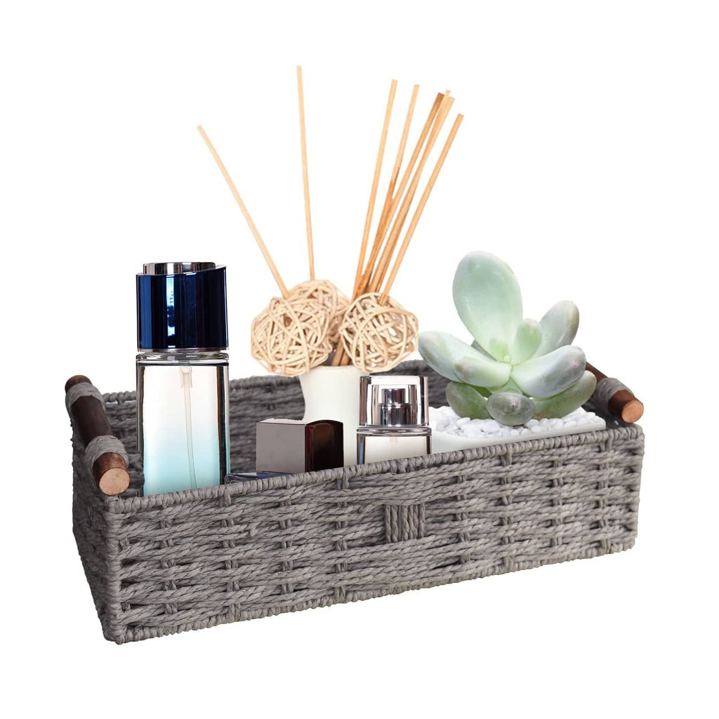 Grey woven storage basket with short wooden handles, holding toiletries and decor items.