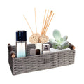Grey woven storage basket with short wooden handles, holding toiletries and decor items.