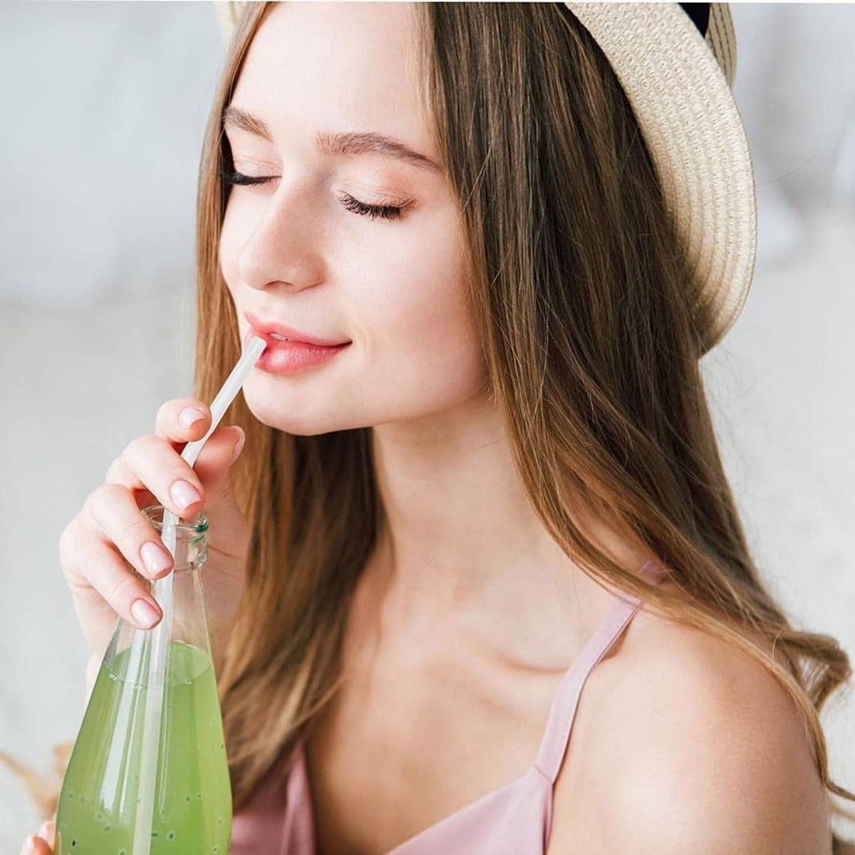 White PLA straw in a drink, held by a woman