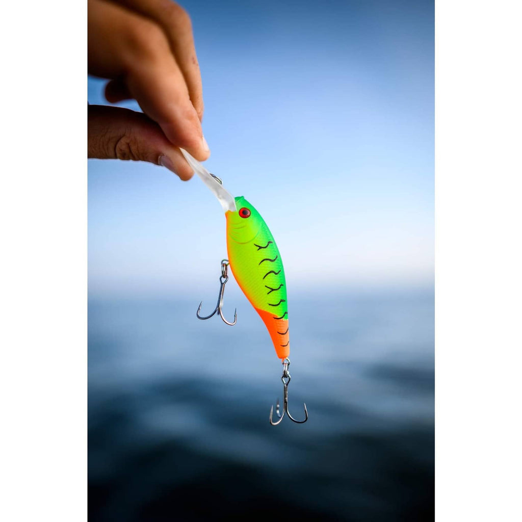 Chartreuse and orange crankbait lure with treble hooks held by hand