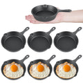 Set of 4-inch black mini cast iron skillets, one held in hand