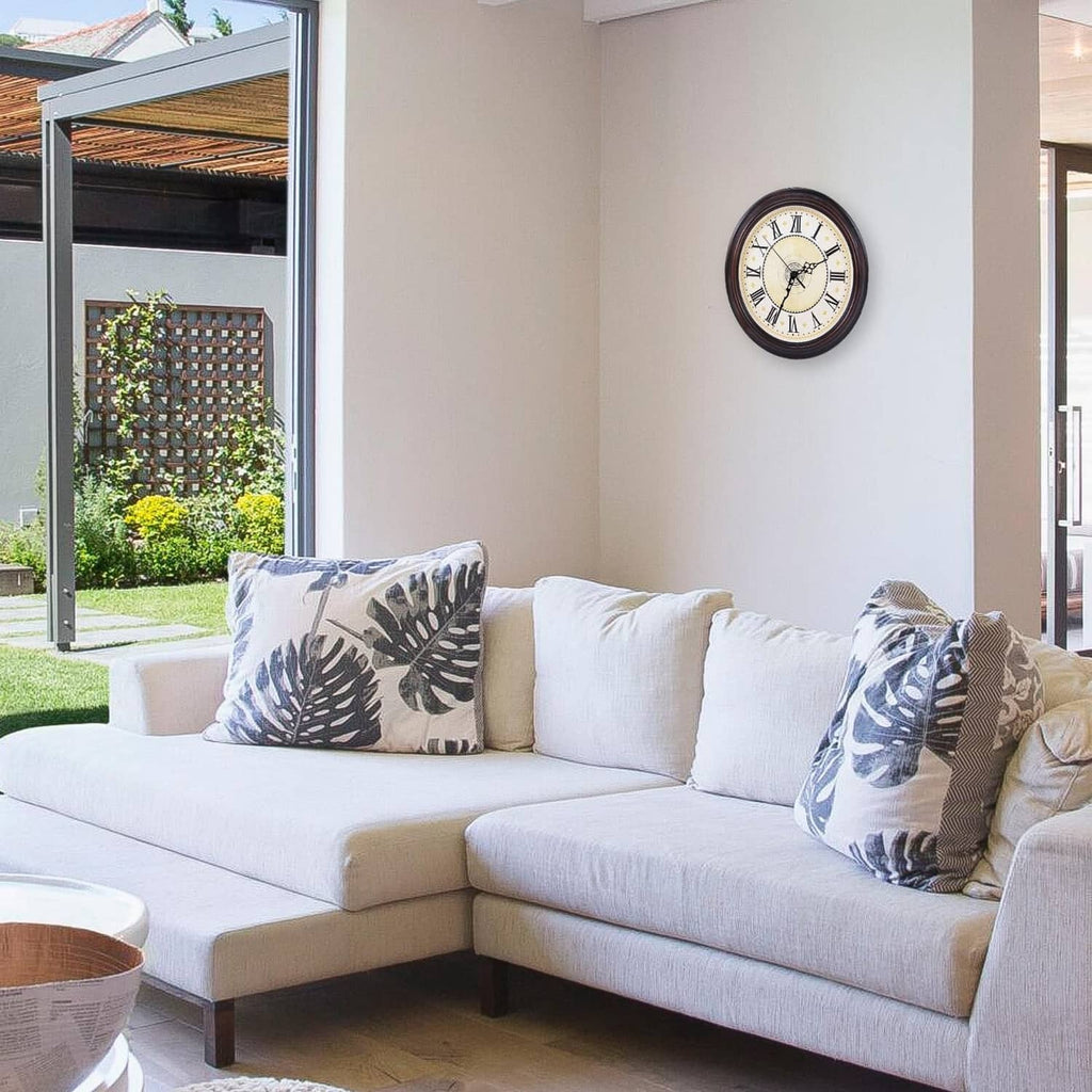 Wall clock with round black frame and white dial above a light-colored sofa