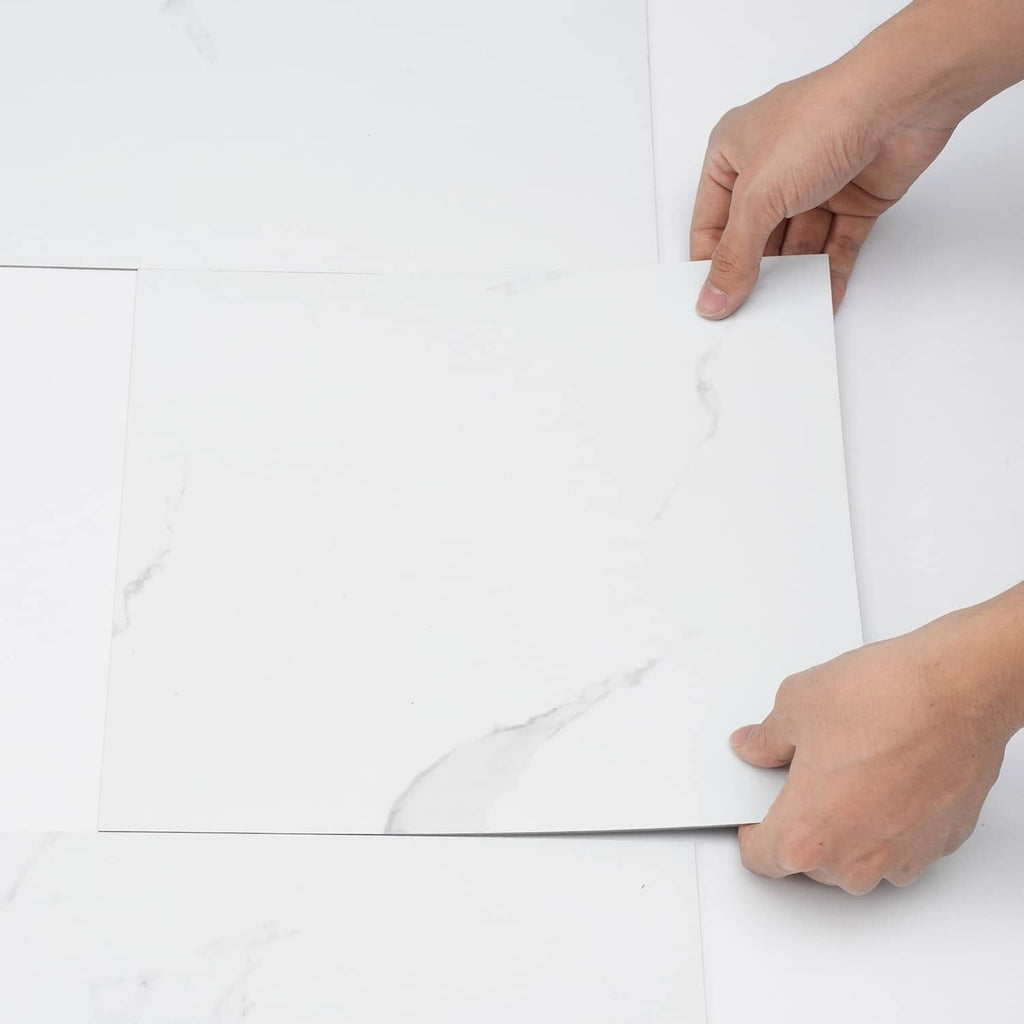 Self-adhesive vinyl floor tile, white marble pattern; hands align two tiles