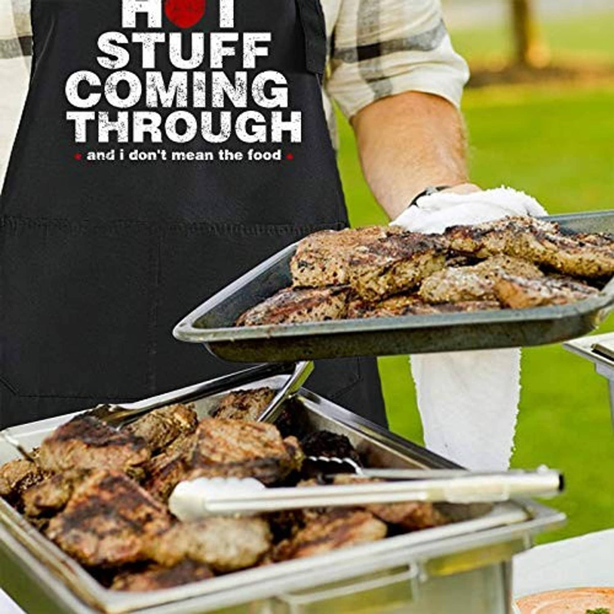 Black chef apron with “HOT STUFF COMING THROUGH” slogan near a grill