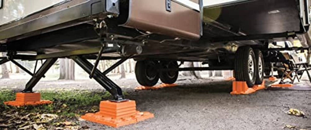 Orange leveling blocks placed under trailer wheels on asphalt