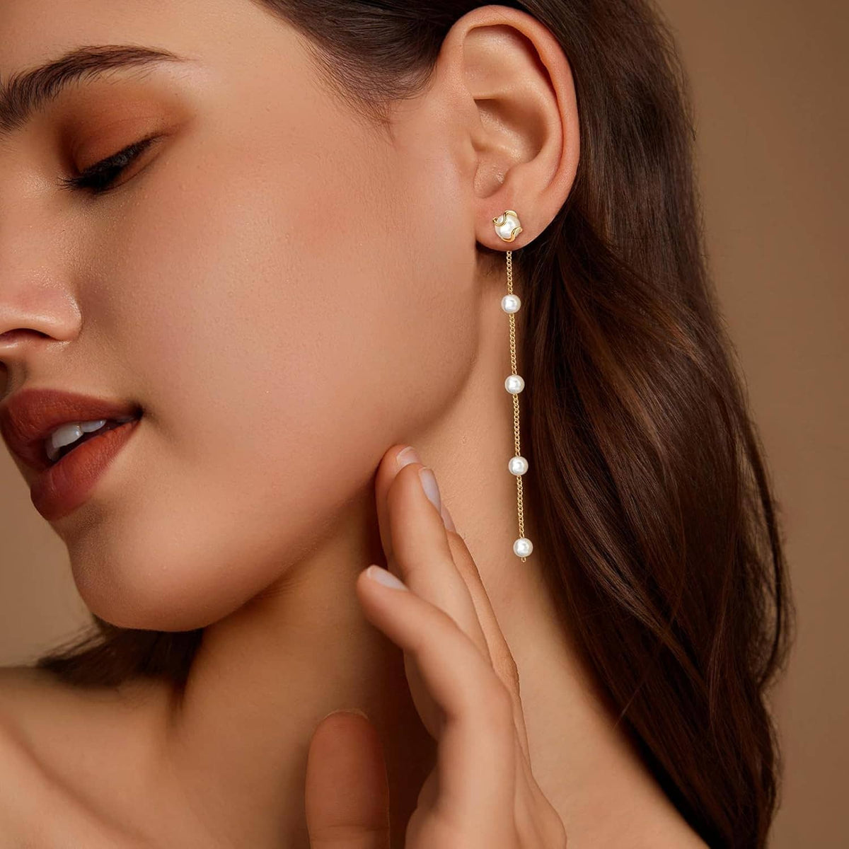 Long gold pearl drop earrings with white pearl dangles on model