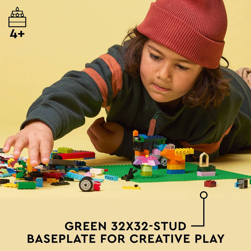 Green square LEGO baseplate with raised studs, held by hands during play.