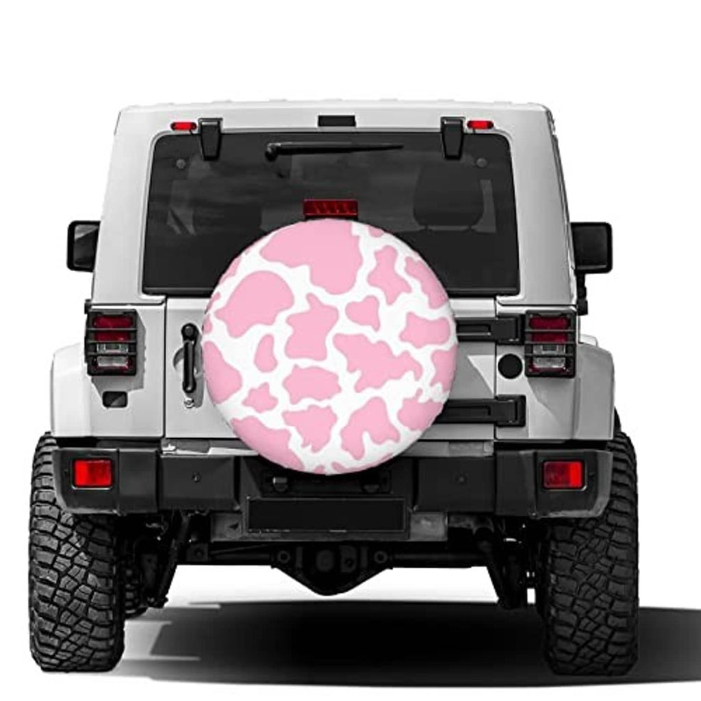 Pink cow-print spare tire cover on the back of a vehicle, round cover with black trim