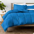 Blue comforter and pillow shams set on bed, quilted puffy design