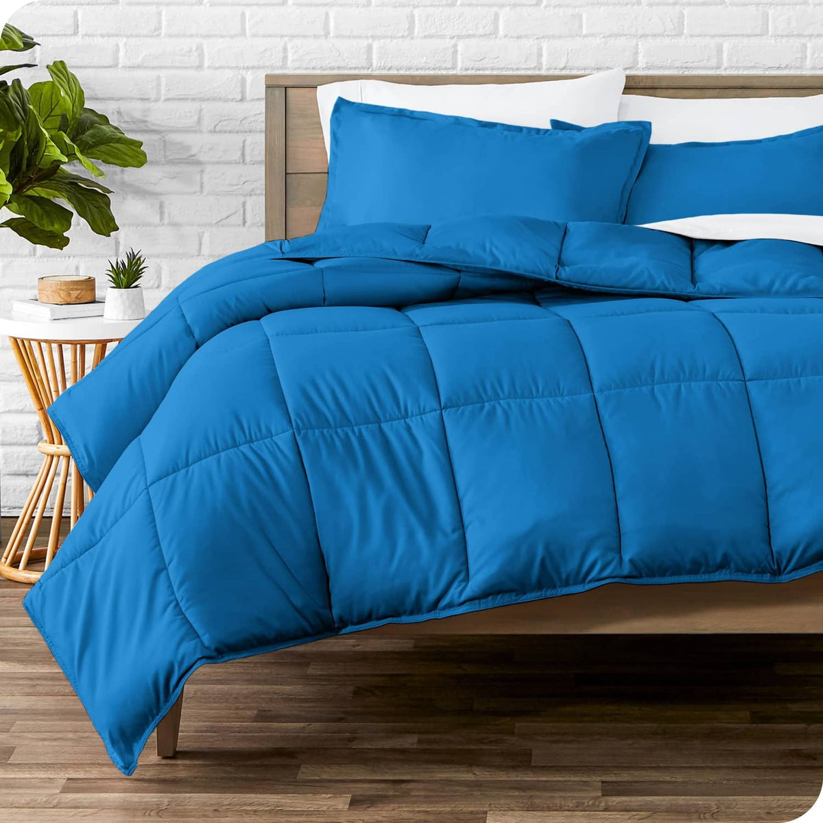 Blue comforter and pillow shams set on bed, quilted puffy design