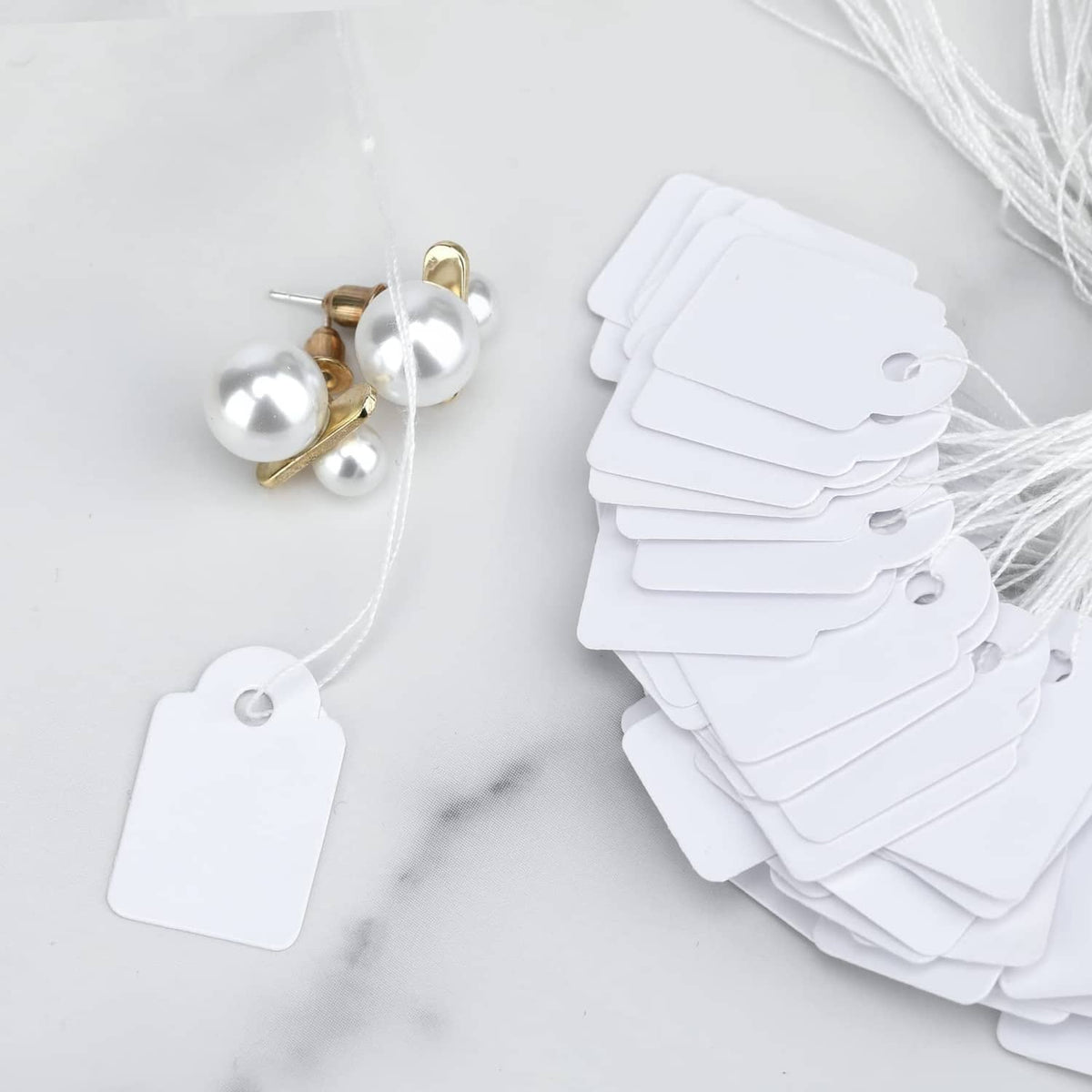 Bundled set of white price tags with attached strings, stacked fan shape