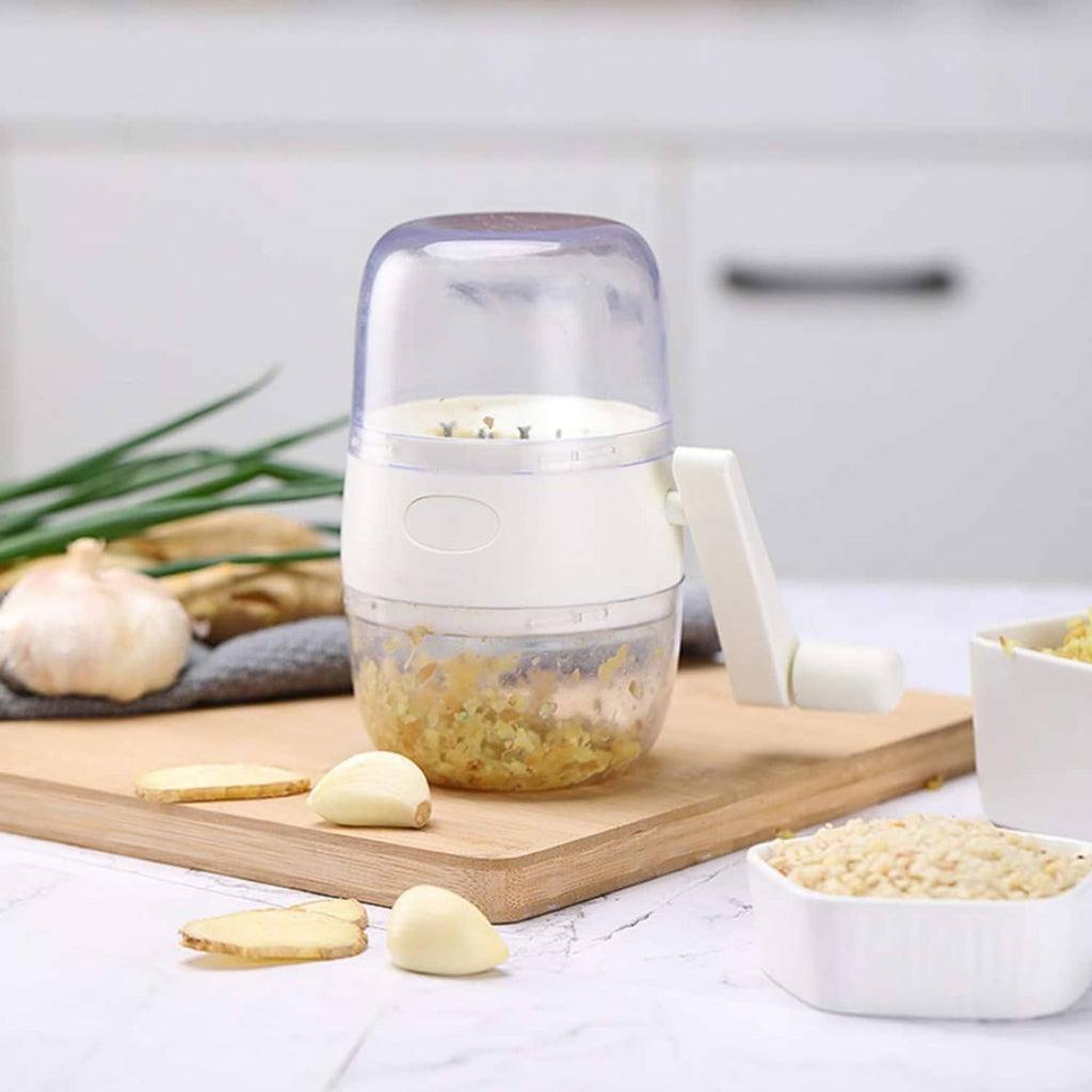 Portable nut chopper with clear bowl and white side crank, on a wooden board